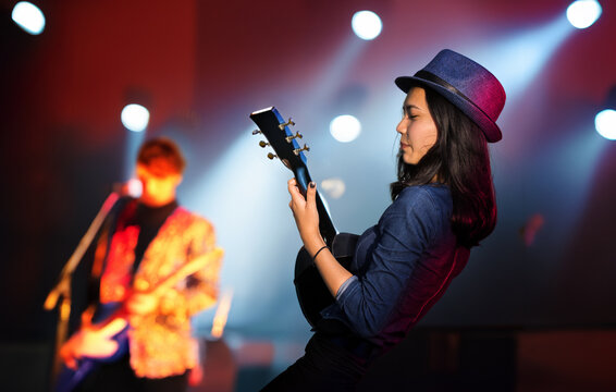 Asian woman playing guitar on music concert stage