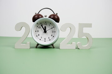 Happy new year 2025 and alarm clock on green background