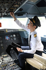 Pilot sitting in the cockpit of an airplane and adjusting controls on the overhead panel
