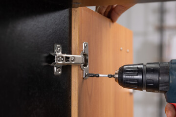 Worker fixing cabinet door hinge on cabinets.