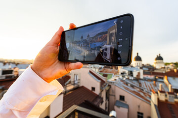 Female hands holding smartphone and making photos in Lviv.