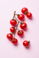 A bunch of fresh, vibrant cherry tomatoes still attached to the vine, set against a soft pink background, showcasing their juicy ripeness and natural beauty.