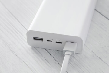 Close up of white power bank with multiple usb ports, one with plugged cable. Charging devices with...