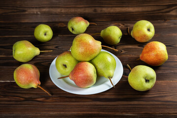 Fresh pears on plate on wooden background. Selective focus