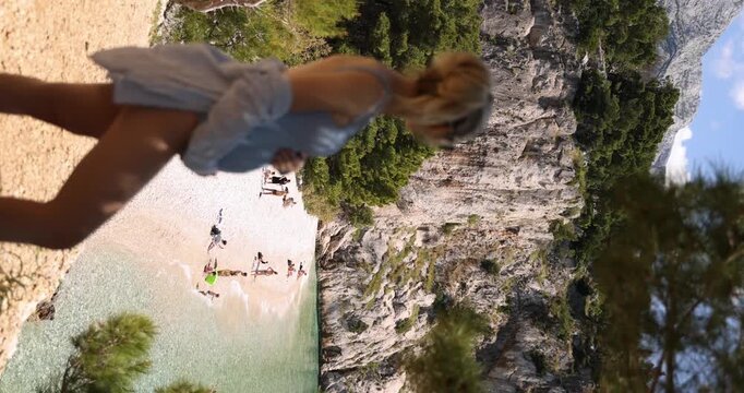 Profile view of pregnant woman in swimwear overlooking Nugal Beach, vertical