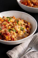 Homemade One-Pot Cheesy Taco Pasta in a Bowl on a black background, side view.