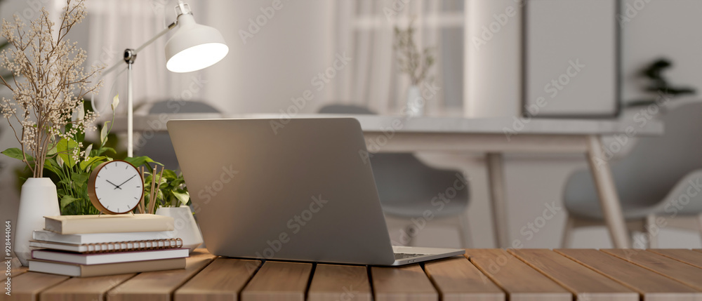 Poster a back view image of a laptop computer and decor on a wooden table in a minimalist room.