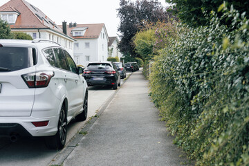 Cars parked near private houses on the roadway.