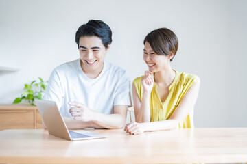 家のリビングでパソコンを見る日本人夫婦