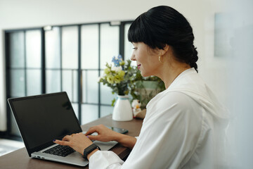 Mature woman registrating clients online on laptop while standing behind the registration desk