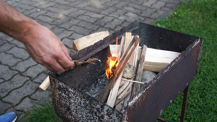 A hand is starting a fire in a grill for barbeque