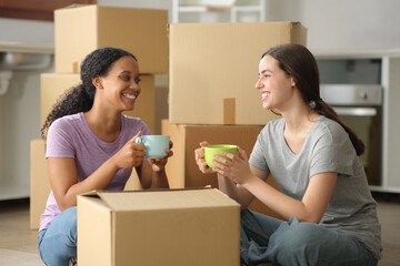 Interracial roommates talking and drinking moving home