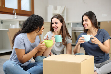 Three happy roommates talking and resting moving home