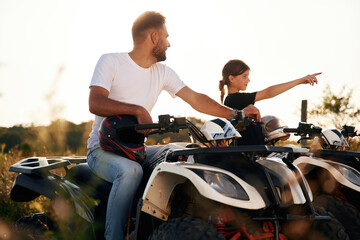 Girl is showing the way. Father and daughter are with ATV outdoors © standret