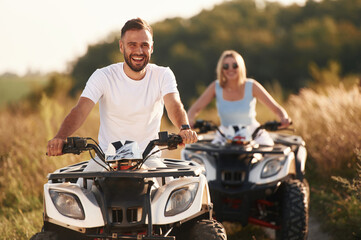 Cheerful facial expression. Man and woman are on ATV outdoors