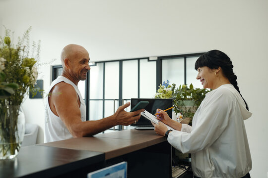 Receptionist discussing timetable with client of wellness club