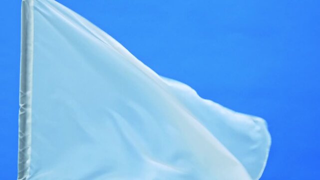 Slow motion video of white flag waving on blue background