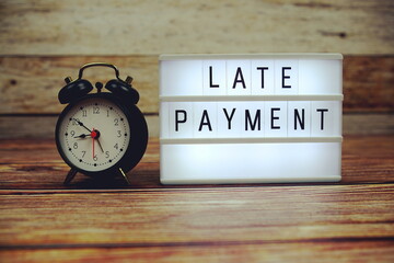 LATE PAYMENT letterboard text on LED Lightbox on wooden background, Business and Finance concept...