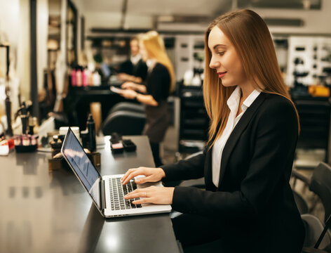 Laptop, work and woman with phone at hair salon for small business, budgeting or expense report