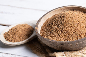 Coconut palm sugar in a coconut bowl on white wooden table background.