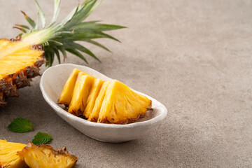 Fresh sliced and cut pineapple pieces on gray table background.