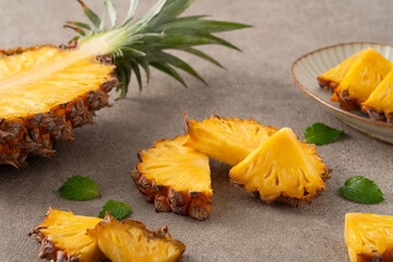 Fresh sliced and cut pineapple pieces on gray table background.