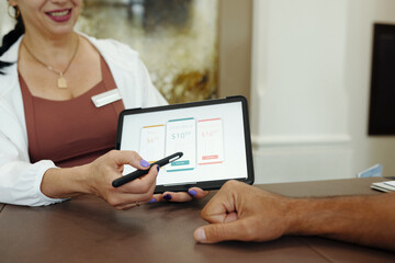 Administrator pointing at digital tablet and consulting client about sport program