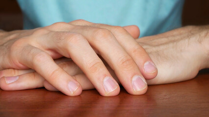 Close up of man's hands folded on a wooden table