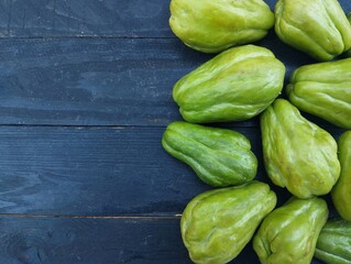 Sechium edule fresh chayote on the black wooden table. Food ingredient, vegetarian cuisine, organic farm plant