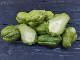 Sechium edule fresh chayote on the black wooden table. Food ingredient, vegetarian cuisine, organic farm plant