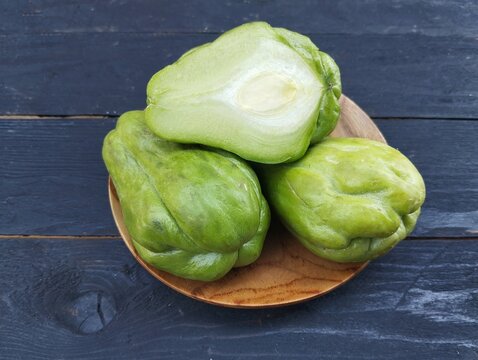 Sechium edule fresh chayote on the black wooden table. Food ingredient, vegetarian cuisine, organic farm plant