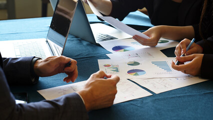 A team of business statisticians analyzes market segments using sales statistics presented in infographics. Trading experts use data charts on paper in the office lobby