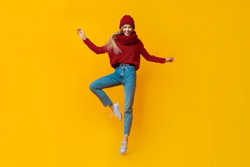 Young beautiful girl in blue warm clothes jumping up, demonstrating dancing moves