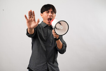 Asian man wearing a dark gray shirt, shouting into a white and red megaphone while raising his hand...
