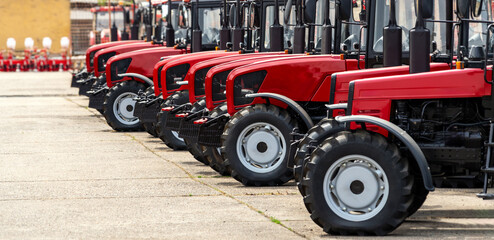Agricultural red coloured tractors in a row. Agricultural equipment dealership background.