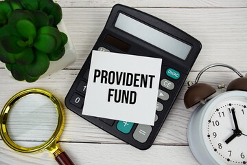 Provident Fund text message with calculate, alarm clock and magnifying glass on wooden background