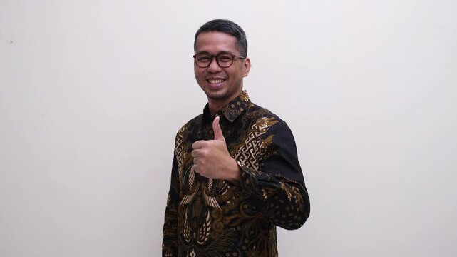 Adult Asian man smiling confident at the camera and give thumbs up