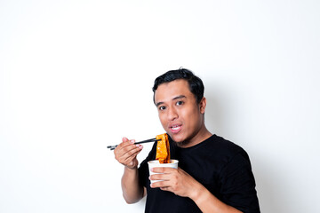 Asian adult man wearing a black t-shirt posing eating Korean specialty food odeng isolated white background