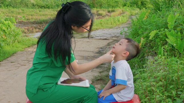 Asiatic nurse doctor month dental check up&nbsp;to young children in south east Asia remote rural village outdoor charity hospital prevention disease in kids , Asia healthcare