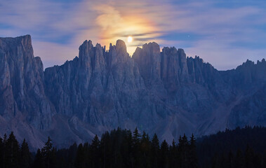 Night photo of Mount Latemar, the moon rises over the mountain range of Bolzano province, Italy