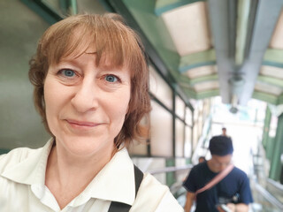 A woman enjoys her journey on an escalator in a vibrant Hong Kong setting. The adventures of a middle-aged female tourist on a trip