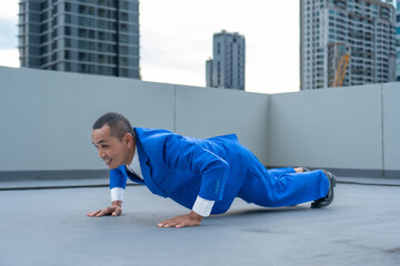 Businessman in a blue suit exercising on a rooftop