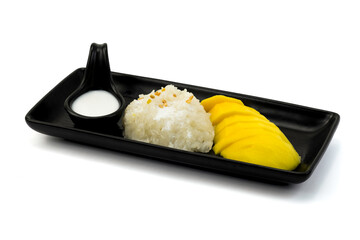 Mango sticky rice in black plate on white background closed up stack. Thai dessert sweet food serving with coconut milk and ripe mango.
