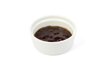 Oyster sauce in white cup on white background closed up.