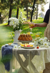 Chamomile flowers, books, glass teapot and cup with herbal tea on table in garden, natural background. summer season. relax time. useful calming tea. tea party outdoor