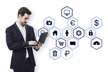 Businessman in a suit using a laptop with virtual icons on white background, representing modern technology and digital business concepts
