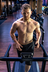 Athlete on a treadmill in the gym. Shirtless man in the gym. Sports lifestyle.