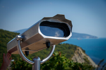 Observation binoculars with a view of mountains and sea on an observation deck