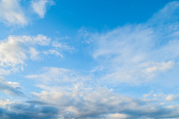 Blue sky landscape in picturesque tones, dramatic clouds in the sunset sky lit by evening sunlight, sunset sky background