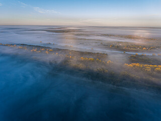 Thick Morning Fog over River and Bank with Treetops Visible